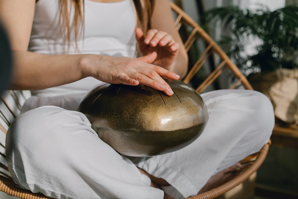 A person sits meditating, playing a handpan for relaxation and mindfulness.