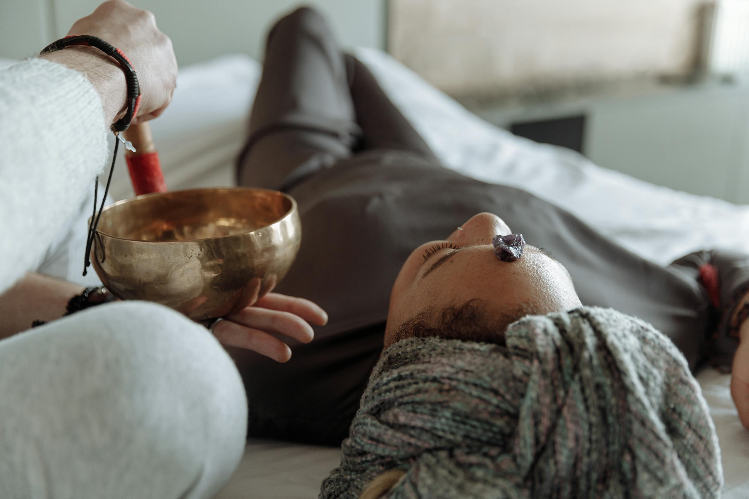 A serene relaxation therapy session with a Tibetan singing bowl and crystal on forehead, promoting spiritual healing.